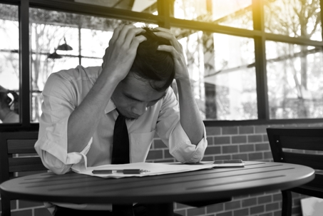 businessman with head in his hands sitting in chair